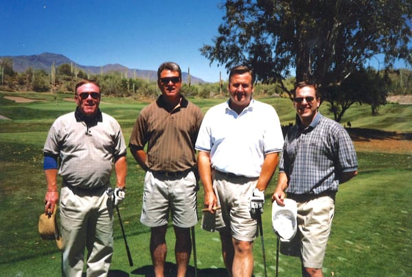 four golfers standing on the tee box